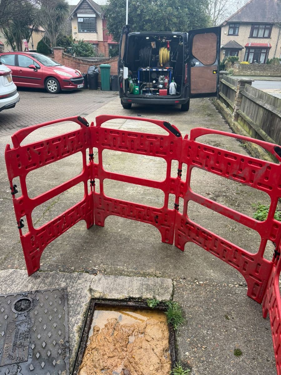 AllTime Drainage van and safety barriers set up at an open manhole on a driveway